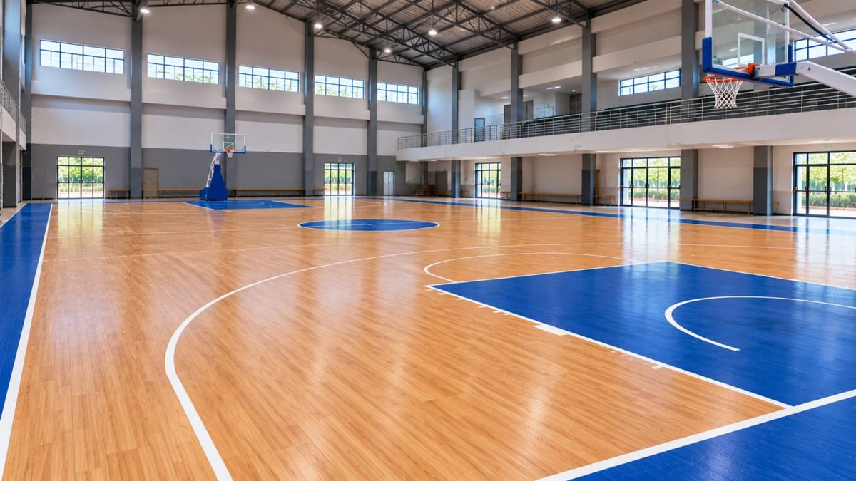 Lantai Lapangan Basket Berkualitas Tinggi 2 Lapangan basket indoor dengan lantai kayu dan garis biru oranye