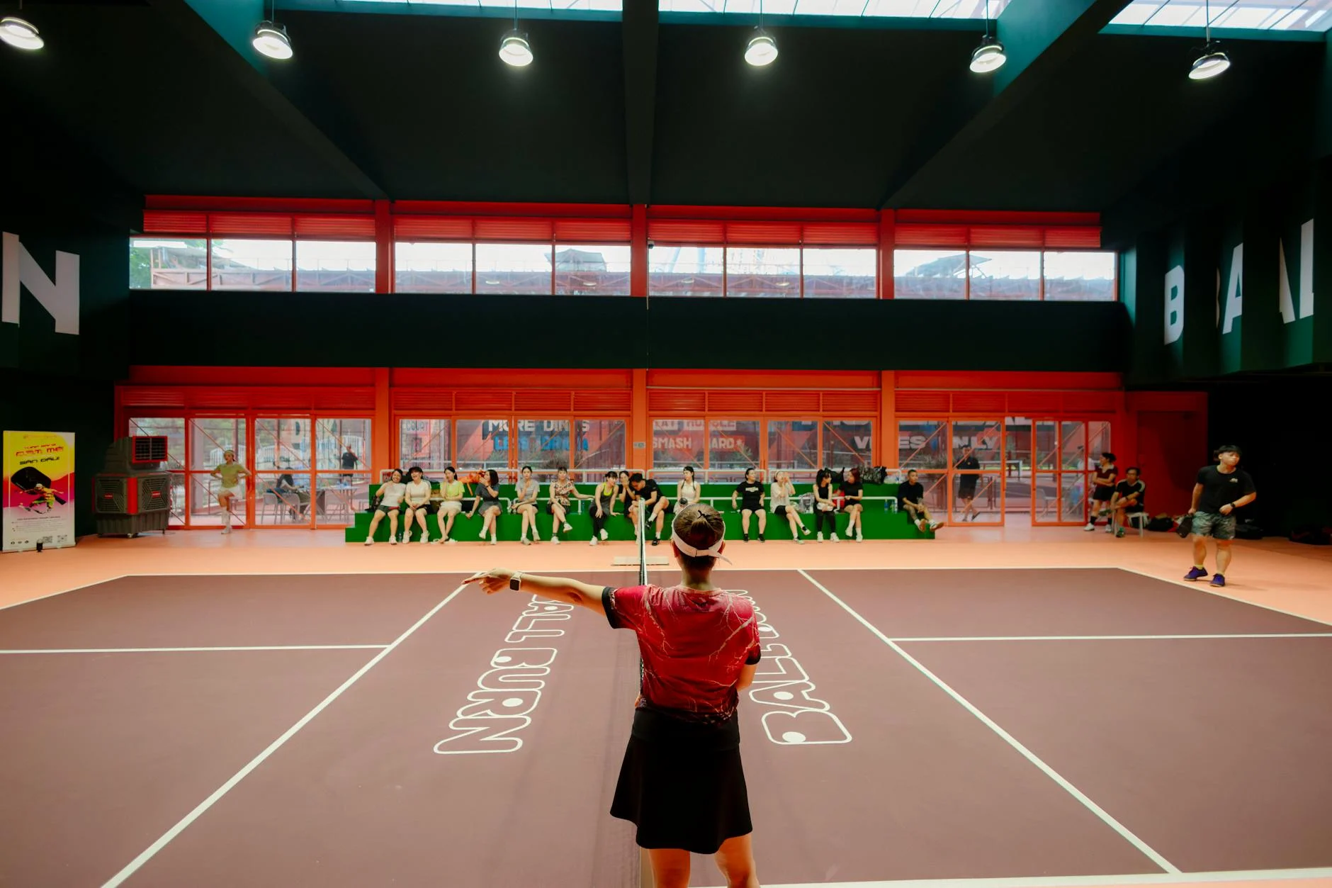 Lapangan badminton dengan garis lapangan dan logo pada lantai kayu indoor