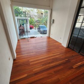 Jasa Pasang Parket Bekasi 2026 - Hasil Rapi & Bergaransi 3 Lantai kayu solid susun lurus mengarah ke pintu masuk kaca kantor di Nganjuk